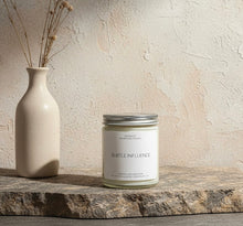 Load image into Gallery viewer, Subtle Influence candle next to a vase on a stone surface with a neutral background