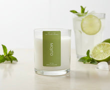 Load image into Gallery viewer, Clear tumbler jar candle placed on a light brown table next to a glass of mojito cocktail with lime and mint leaves, suggesting a crisp, minty, and zesty cocktail aroma.