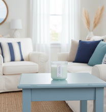 Load image into Gallery viewer, Black Sea candle styled on a coffee table in a white and blue beach house.