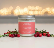 Load image into Gallery viewer, Candle labeled 'Prosecco' with cranberries and rosemary on a light background