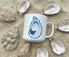 Load image into Gallery viewer, White mug with an oyster design on sand with shells around