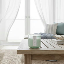 Load image into Gallery viewer, Sea Mist candle styled on a wooden coffee table in a coastal living room.