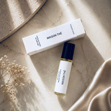 Load image into Gallery viewer, MAISON THÉ perfume oil from the Maison de Parfum collection with matching white box on a light stone surface. The scene includes soft beige fabric and dried flowers in a styled flat-lay composition.

