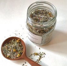 Load image into Gallery viewer, open jar of Herbal Recovery bath tea with a wooden spoon filled with dried botanicals on a white background.

