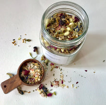 Load image into Gallery viewer, Open jar of Evening Calm bath tea with a wooden  scoop filled with dried botanicals on a white background.
