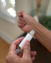 Load image into Gallery viewer, Hand holding a perfume roller bottle with a soft blurred indoor background.

