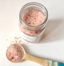 Load image into Gallery viewer, Open jar of Harbor Reset bath soak with a wooden scoop filled with pink bath salts on a clean white background.
