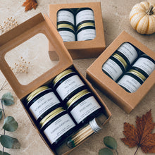 Load image into Gallery viewer, Fall candle gift sets featuring four amber jar candles—Fall in Love, Autumn in My Heart, Pumpkin Everything, and Spiced Maple—with a vial of matches in kraft boxes on a natural stone surface with subtle autumn décor.
